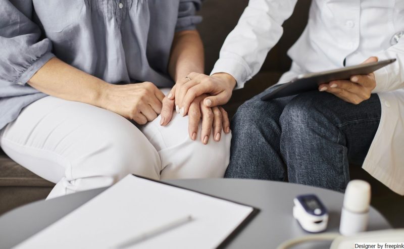 mulher com tablet em uma das mãos e na outra segura a mão de outra mulher representando a terapia.