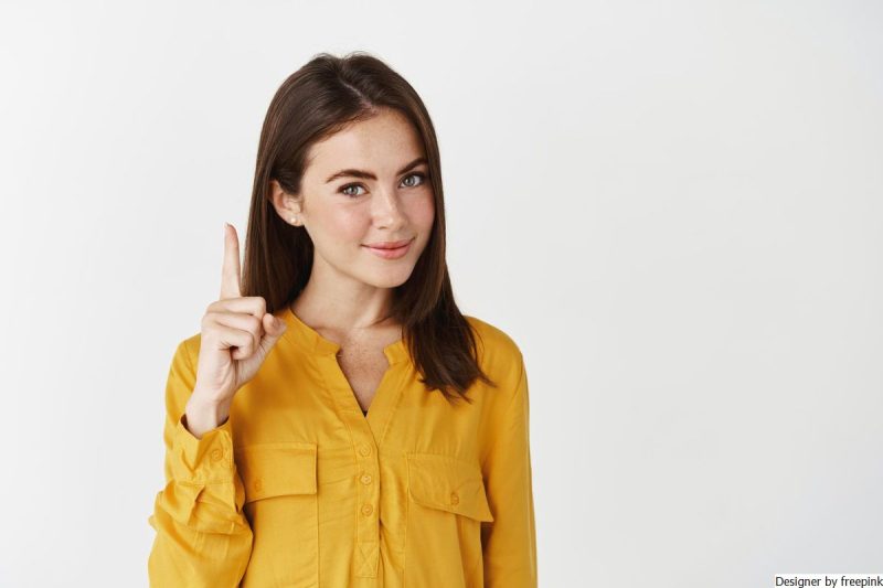 mulher jovem, usa blusa amarela, sinaliza a importância de ter cuidado com uma ação impulsiva. 