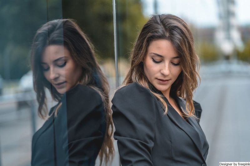 mulher, jovem. loira, veste preto, olhando para baixo simbolizando a necessidade de agradar